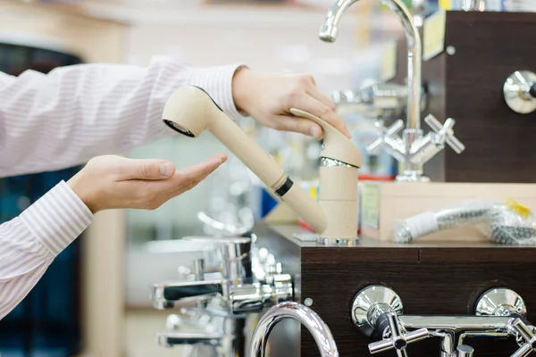 DIY department shopping: closeup on businessman hands choosing and touching for buying faucet, crane or water tap on shop display