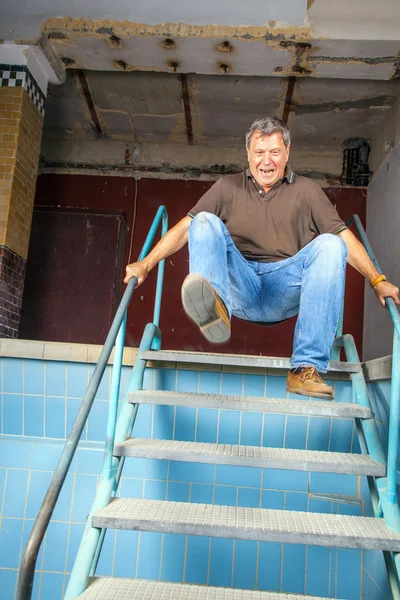 Man jumping down the stairs of an old waterless pool