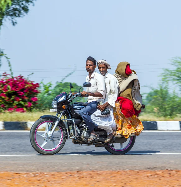 Mother, father and small child riding on scooter through busy hi