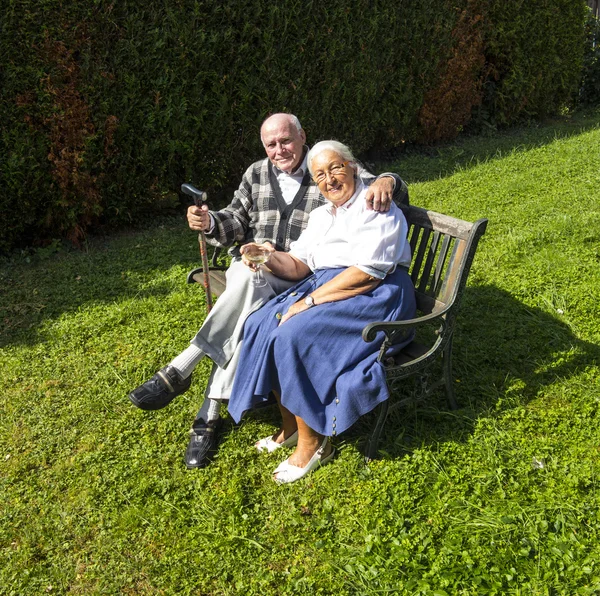 Elderly couple sitting in their garden and enjoy life