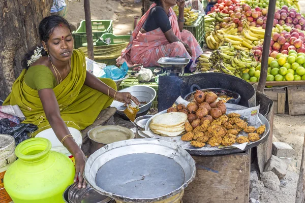 Indian women in brightly colored saris selling bread and crispy