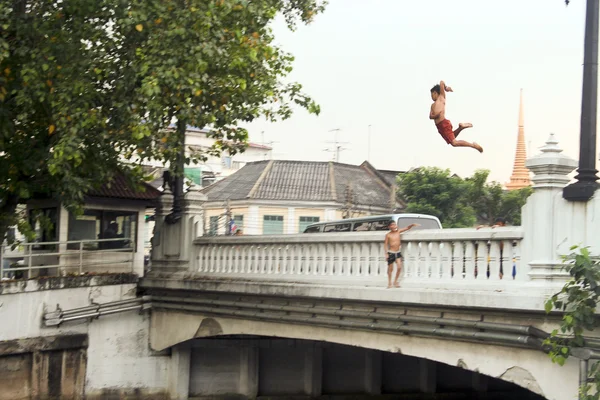 Children jump from a bridge in the river