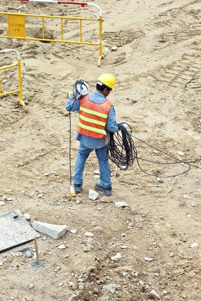Building worker at the building site carrying an electrical cabl