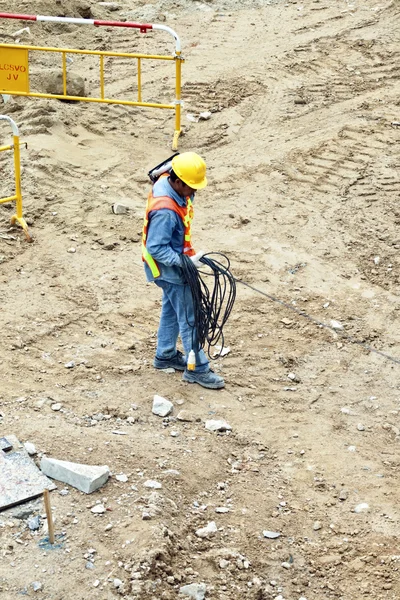 Building worker at the building site carrying an electrical cabl