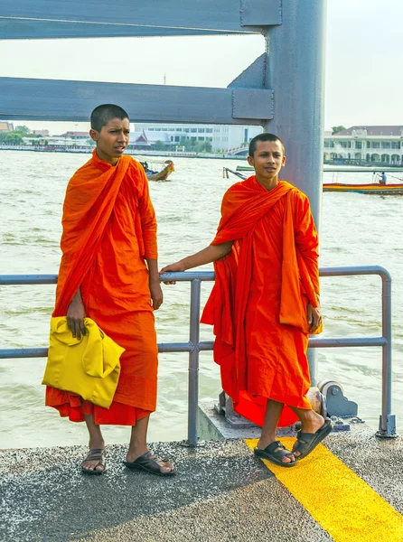 Two teenage monks wait for the ferry in Bangkok