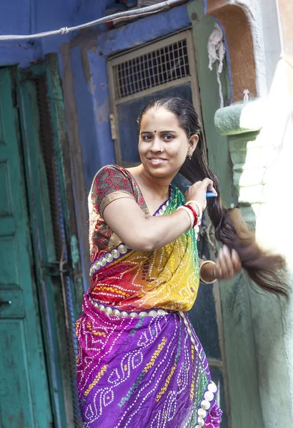 Indian woman combs her hair at her home