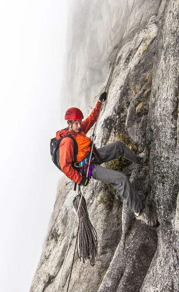 Climber rappells down a cliff.