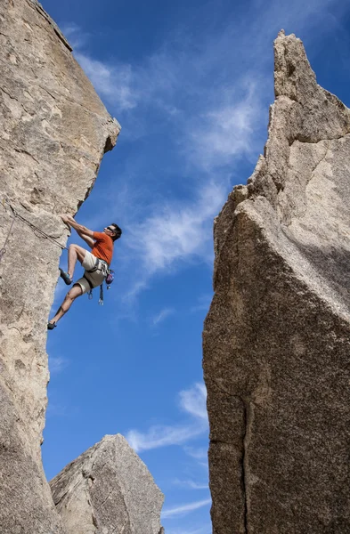 Climber struggles up a cliff.