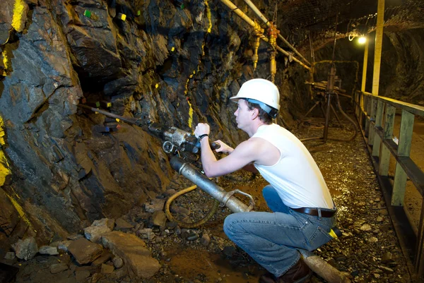 Underground miner drilling into rock