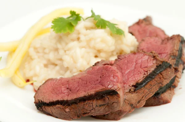 Medium rare beef tenderloin grilled to perfection with creamy risotto and yellow string beans