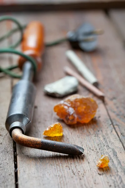 Old soldering iron with rosin and solder on wooden table