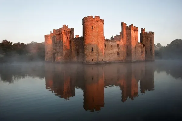 Stunning moat and castle in Autumn Fall sunrise with mist over m