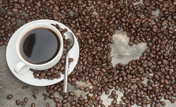 Black coffee surrounded by beans with heart shaped hole, coffee