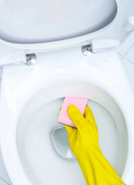 Hands on yellow gloves cleaning a WC