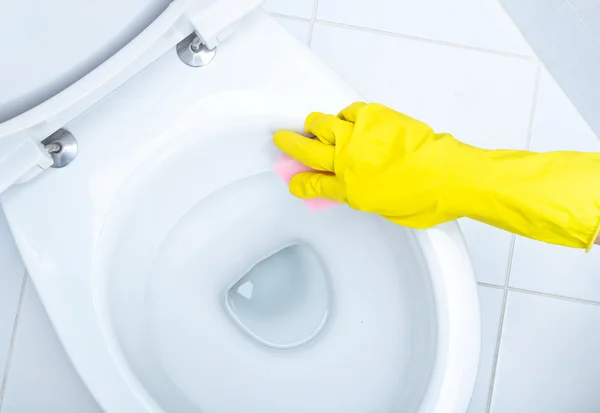 Hands on yellow gloves cleaning a WC