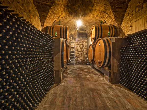 Wine bottles and oak barrels in cellar