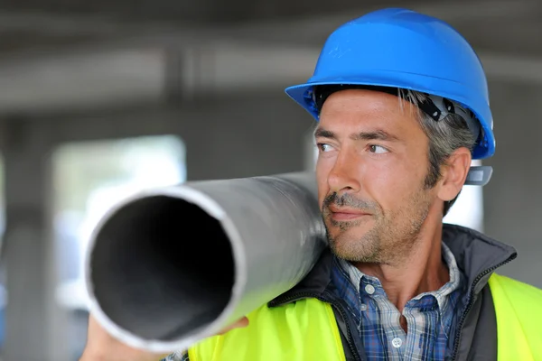 Construction worker on site holding pipe