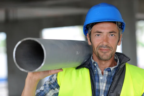 Construction worker on site holding pipe