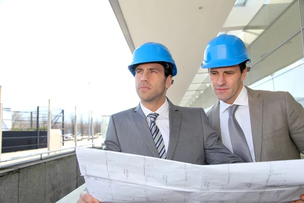 Architects checking construction site with plan outside — Stock Photo #13932009
