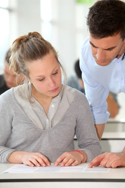 Teacher assisting student girl in class