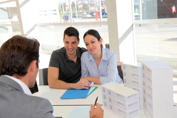 Couple in real-estate agency signing property loan contract