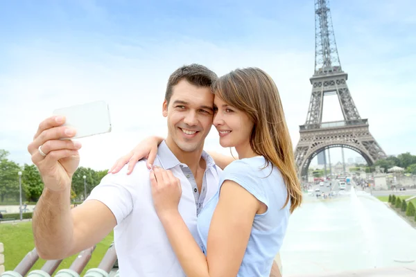 Couple in Paris taking pictures in front of Eiffel Tower