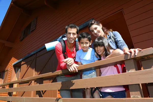 Portrait of family standing on log cabin front door