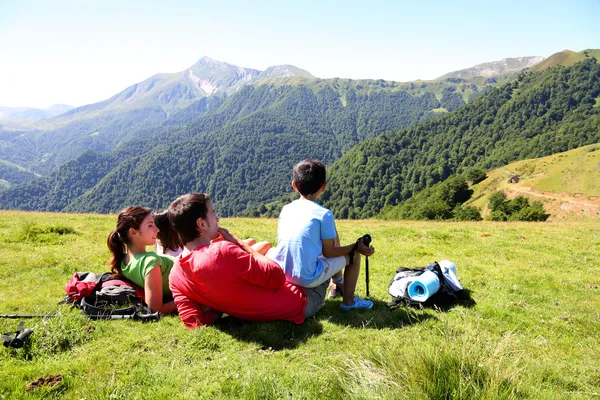 Family laying down the grass enjoying mountain view