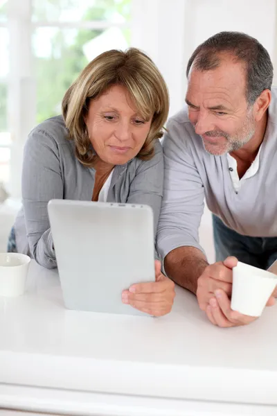 Senior couple drinking coffee in front of tablet