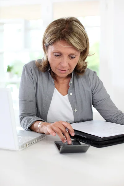 Senior woman pensioner calculating bills