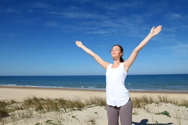 Woman breathing with arms up by the beach — Stock Photo #13941643