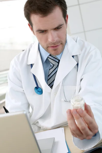 Doctor with laptop computer checking medicine composition