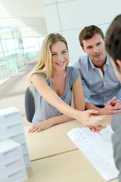 Couple shaking hand to real-estate agent in office