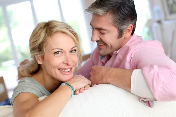 Middle aged couple relaxing in sofa at home