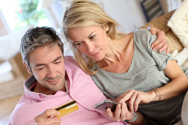 Upper view of couple paying with credit card on mobile phone