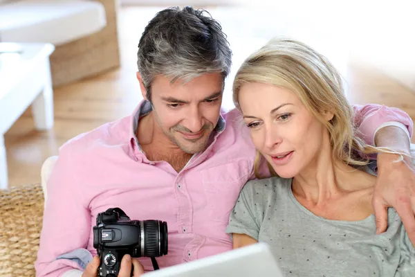 Couple at home looking at pictures on electronic tablet