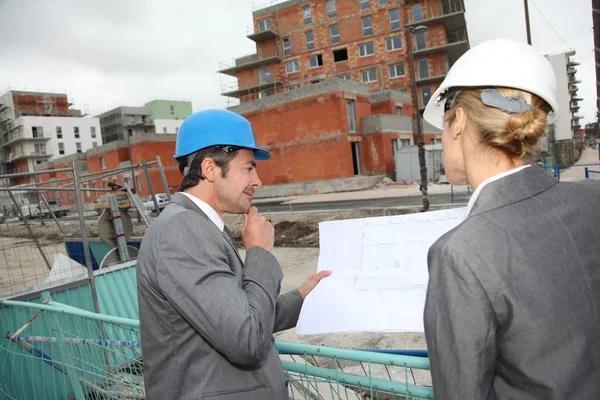 Construction engineers checking plans on building site