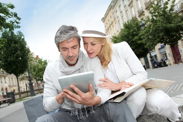 Couple visiting city with help of map and electronic tablet