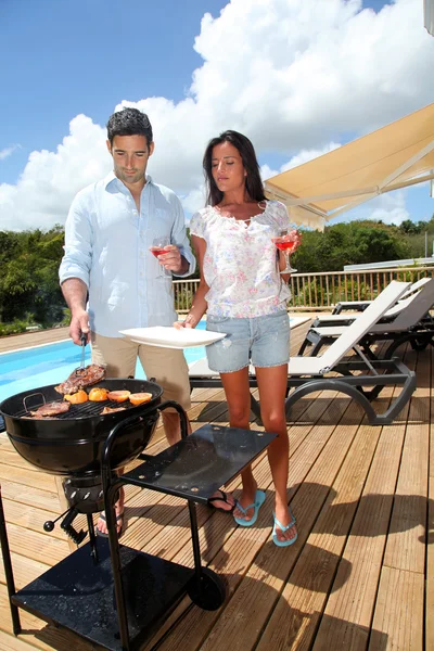 Young couple cooking dinner on barbecue grill