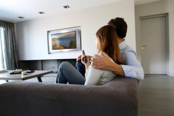 Back view of couple at home watching tv