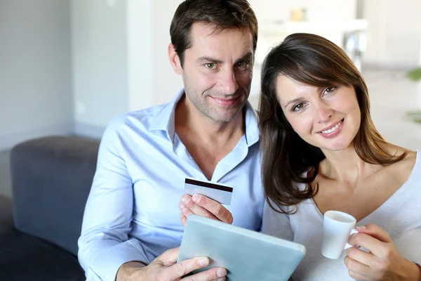 Mature couple at home using credit card to shop online