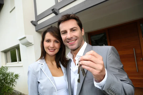 Couple in front of new home holding door keys