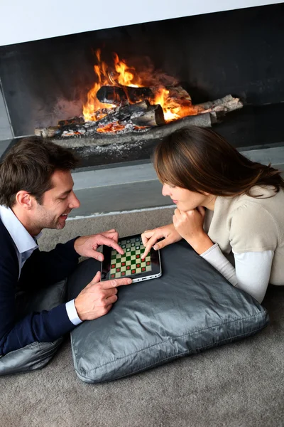 Couple sitting by fireplace and websurfing with tablet