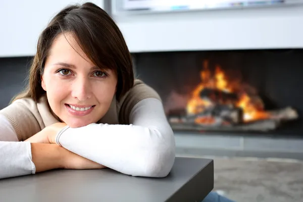 Beautiful woman sitting by fireplace at home