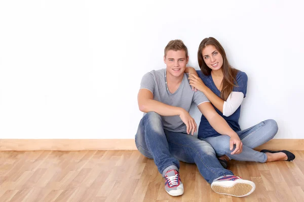 Couple of teenagers sitting against white wall