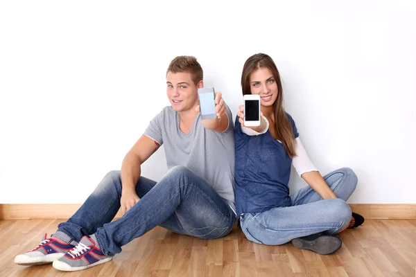 Teens showing mobile phones to camera