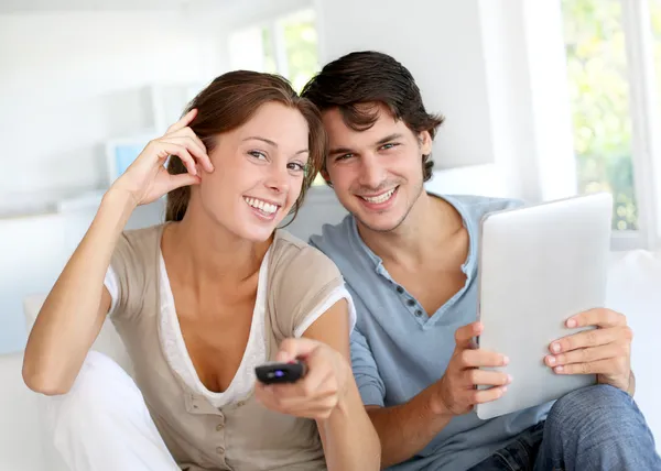 Cheerful couple choosing tv program on digital tablet