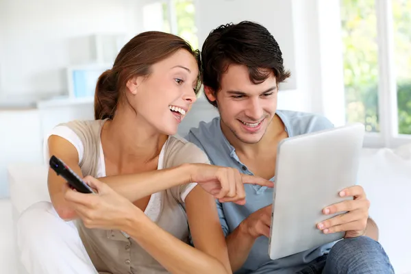 Cheerful couple choosing tv program on digital tablet