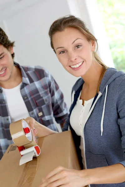 Smiling young woman packing boxes to move out