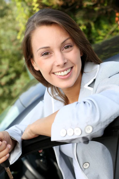 Happy young driver standing by car